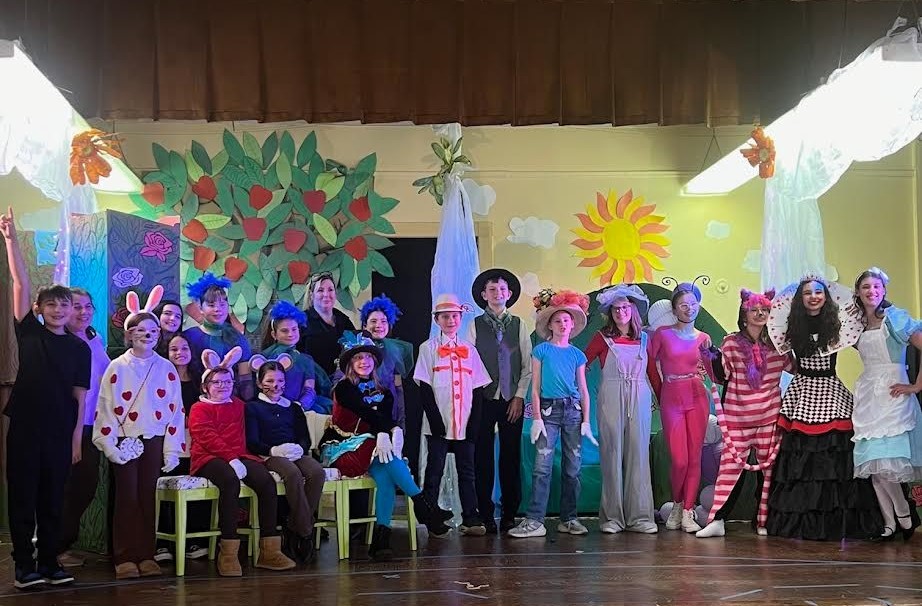 Group of young children in colorful costumes standing on theater stage