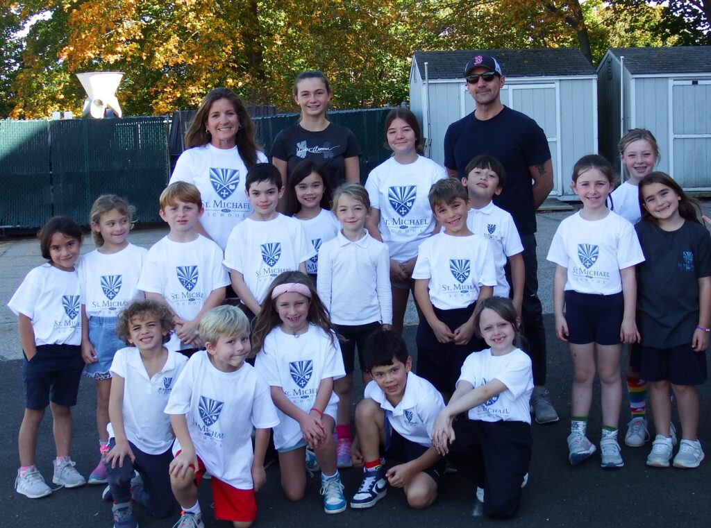 Group of smiling children in white tshirts with blue logos and sneakers with some adult coaches