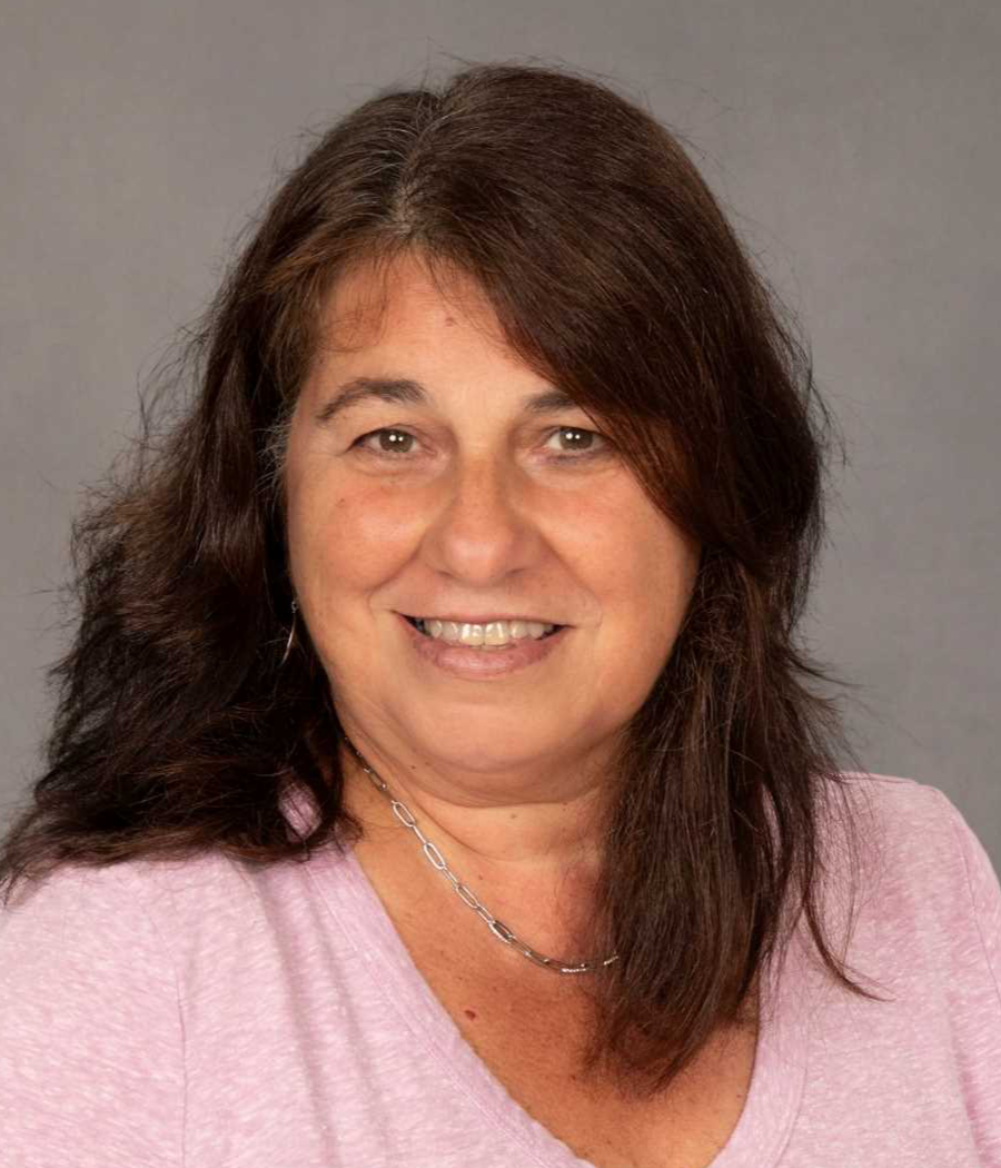 Smiling woman with dark hair wearing a pink shirt