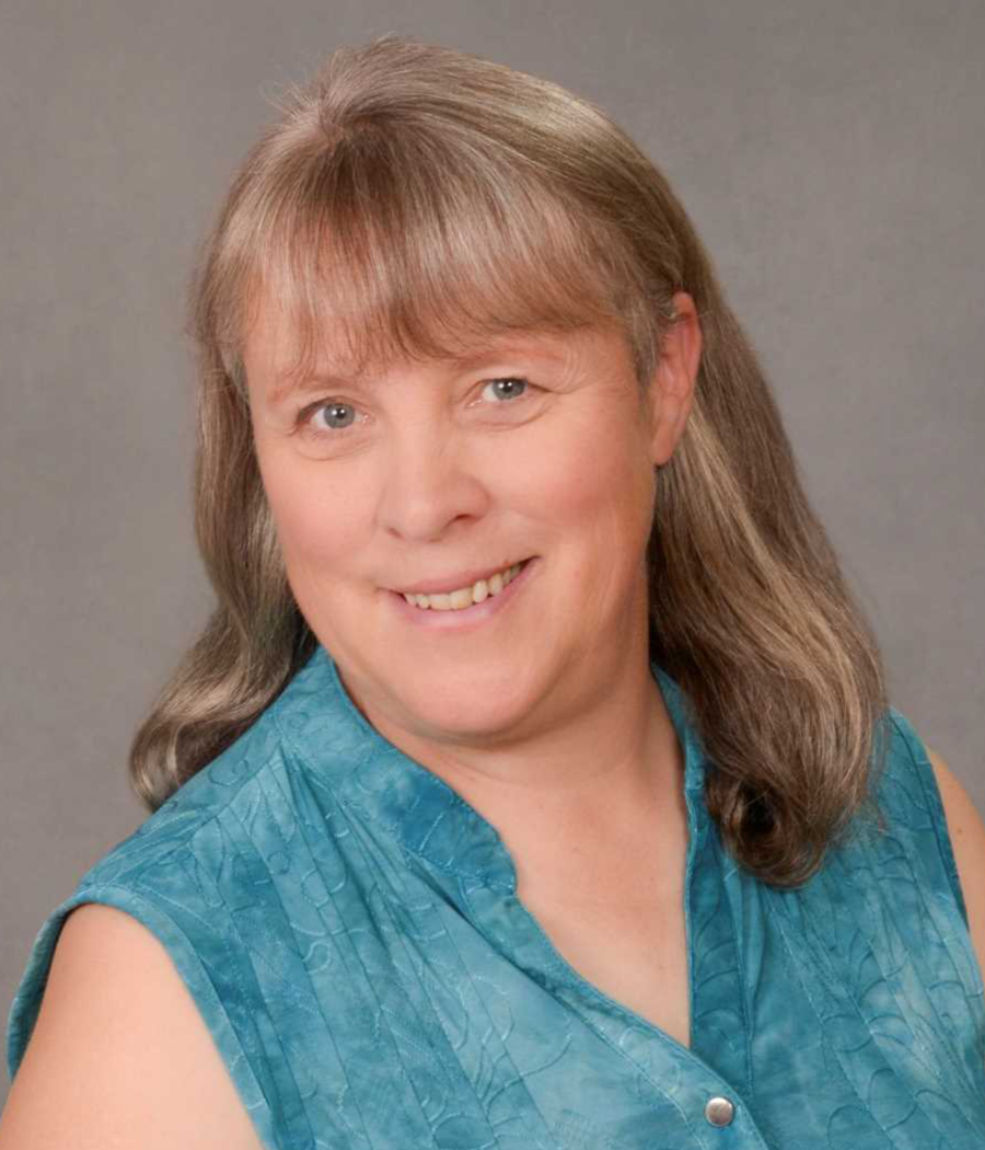 Smiling woman with light brown hair wearing a blue-green shirt