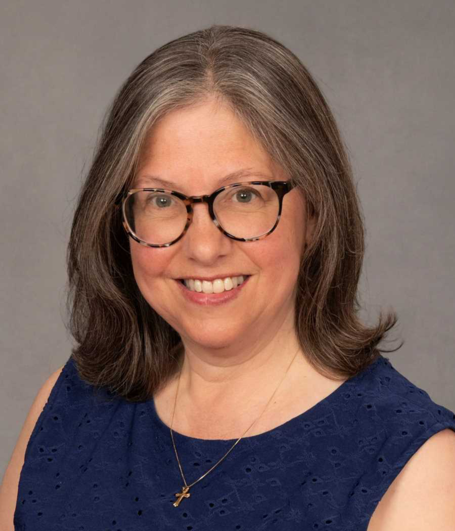 Smiling woman with brown hair wearing dark framed glasses and dark blue shirt