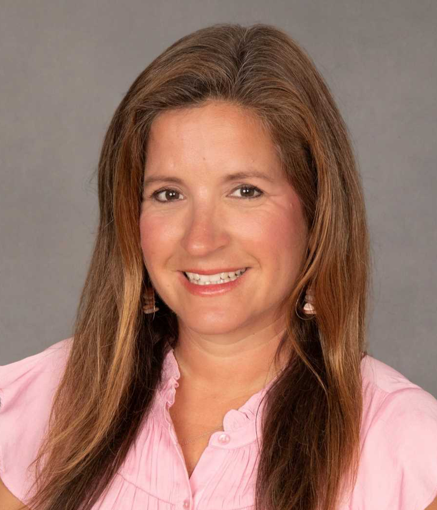 Smiling woman with long brown hair wearing a pink shirt