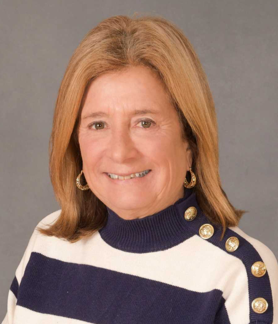Smiling woman with light brown hair wearing a blue and white striped sweater with gold buttons on shoulder