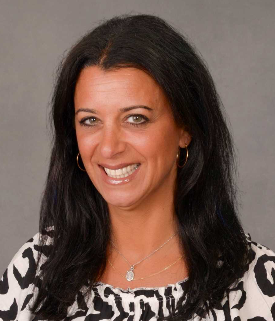 Smiling woman with long black hair wearing a black and white patterned shirt