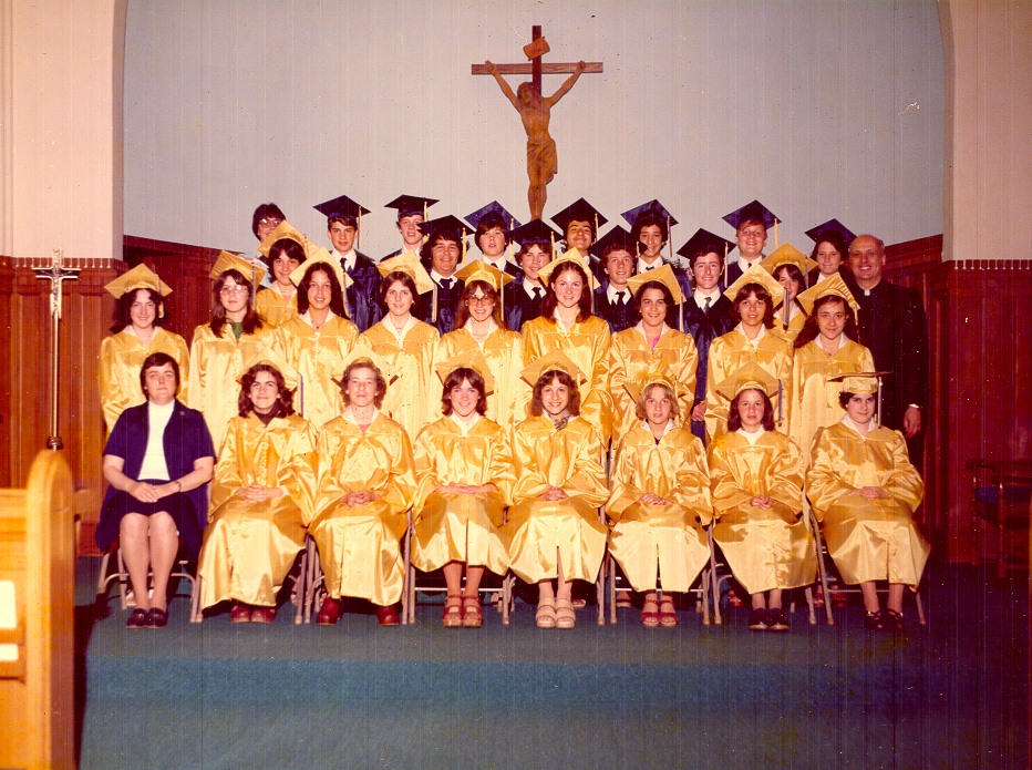 Photo from 1979 of a group on an altar; young men in blue graduation caps and gowns and young women in yellow graduation caps and gowns with a man in a black priest suit and white collar and a woman in a white and dark nun's suit
