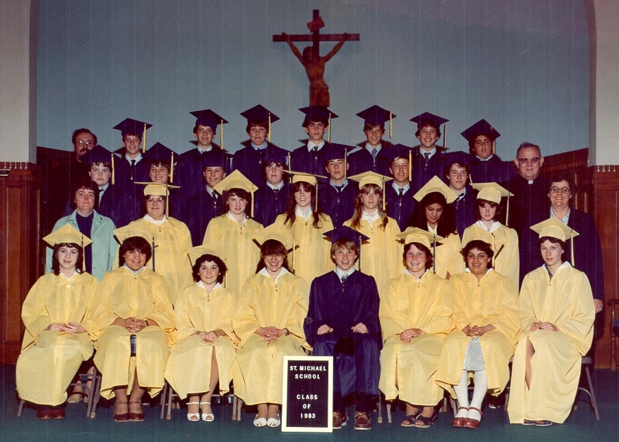 Photo from 1983 on an altar of a group young men in blue graduation caps and gowns and young women in yellow graduation caps and gowns with 2 men in a black priest suits and white collars and two women in a blue dresses